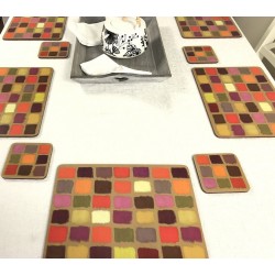 White tablecloth on dining table. Corkbacked funky placemats colourful Harlequin pattern.