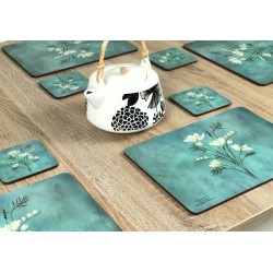 Wooden table with Infinity, teal blue background, corkbacked floral placemats and teapot in centre